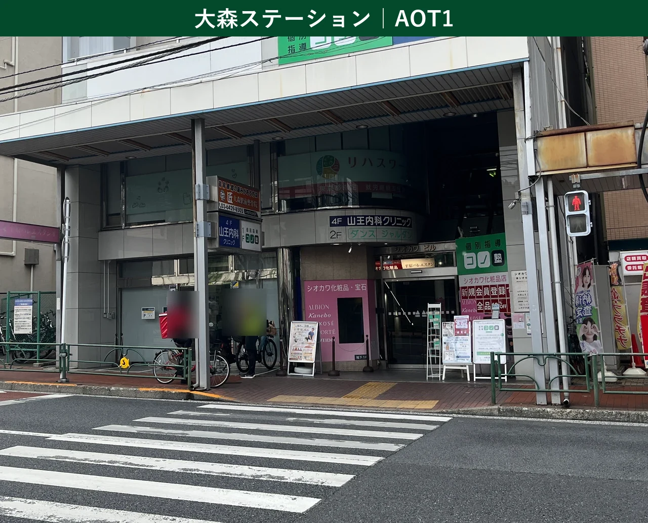 【2026年最新】Amazon Now（アマゾンナウ）大森ステーション（ステーションコード：AOT1／東京都大田区山王2-3-13 シオカワビル1F）の1階ガラス扉とシオカワビル共用入口を示す実写真。大田・品川・山王・平和島エリアの集荷場所。