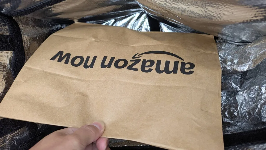 amazon nowのロゴが入った茶色いクラフト紙袋を手で持ったサイズ感